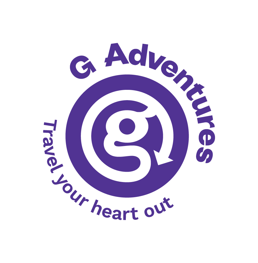 G Adventures circular logo in purple and white with the tagline “Travel your heart out” surrounding a lowercase “g” emblem on a light gray background.