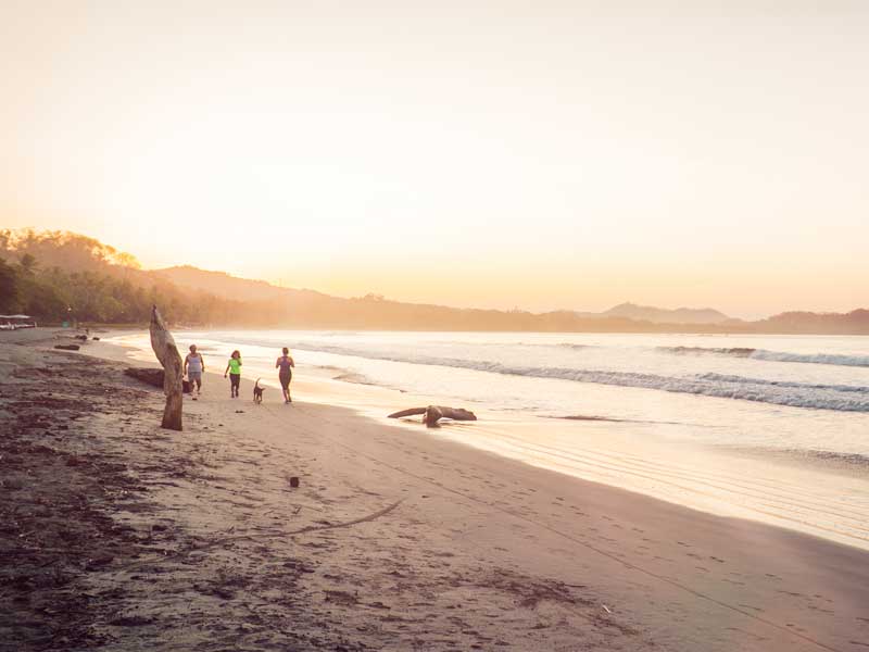 A group of people standing on top of a sandy beach.