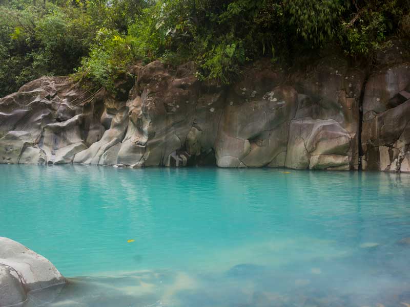A pool of blue water surrounded by rocks and trees.