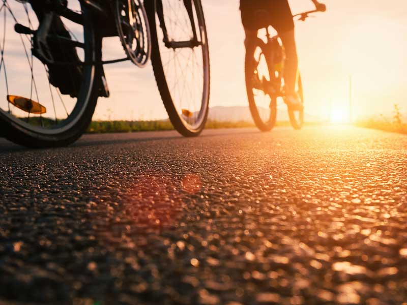 A person riding a bike down a street at sunset.
