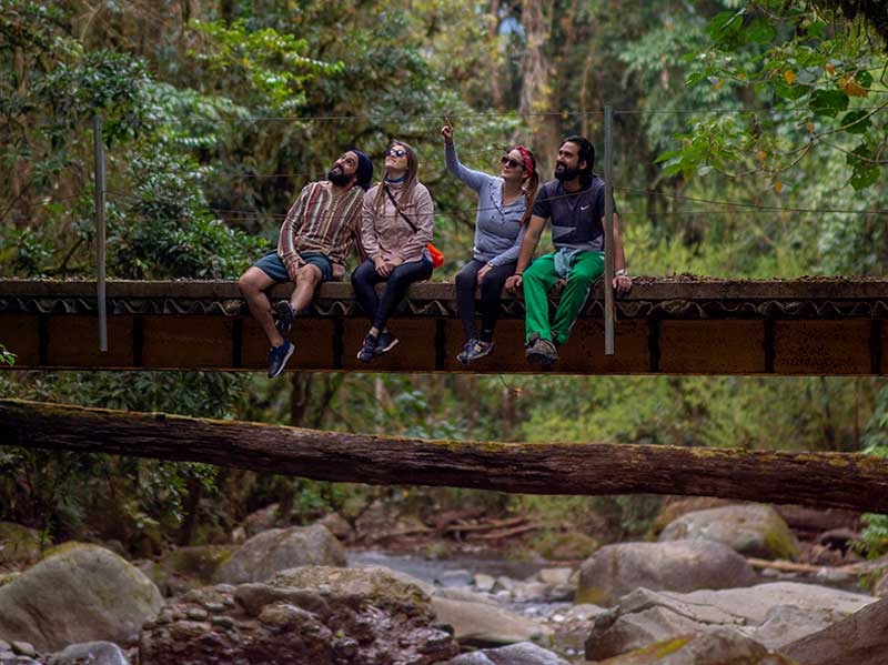 A group of people sitting on a bridge over a river.