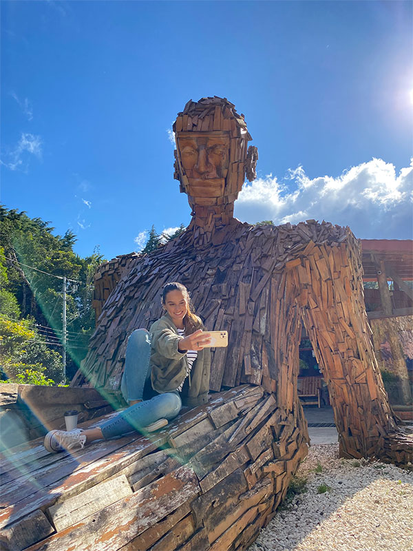 A woman sitting on top of a wooden sculpture.