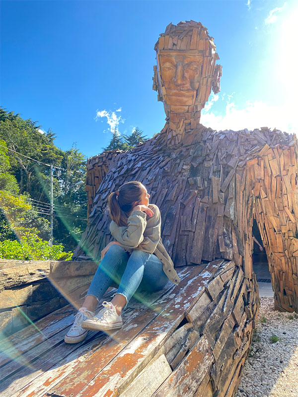 A woman sitting on top of a wooden bench.