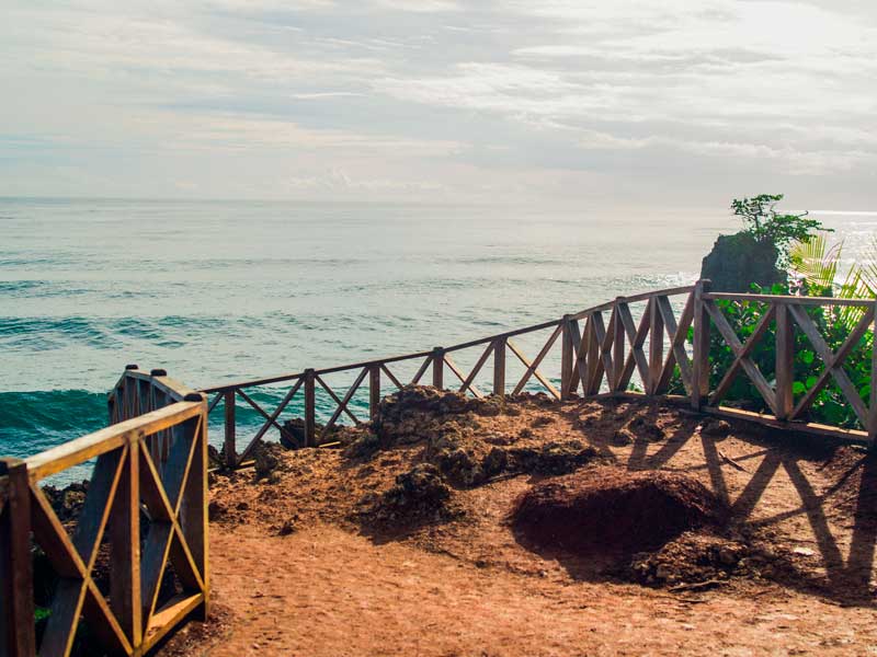 A wooden walkway leading to the ocean on a cloudy day.