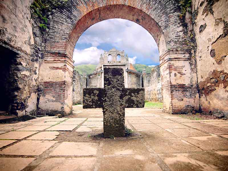 A stone cross sitting in the middle of a courtyard.