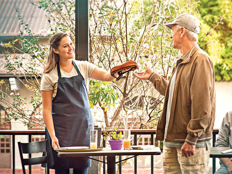 A man handing a tray of food to a woman.