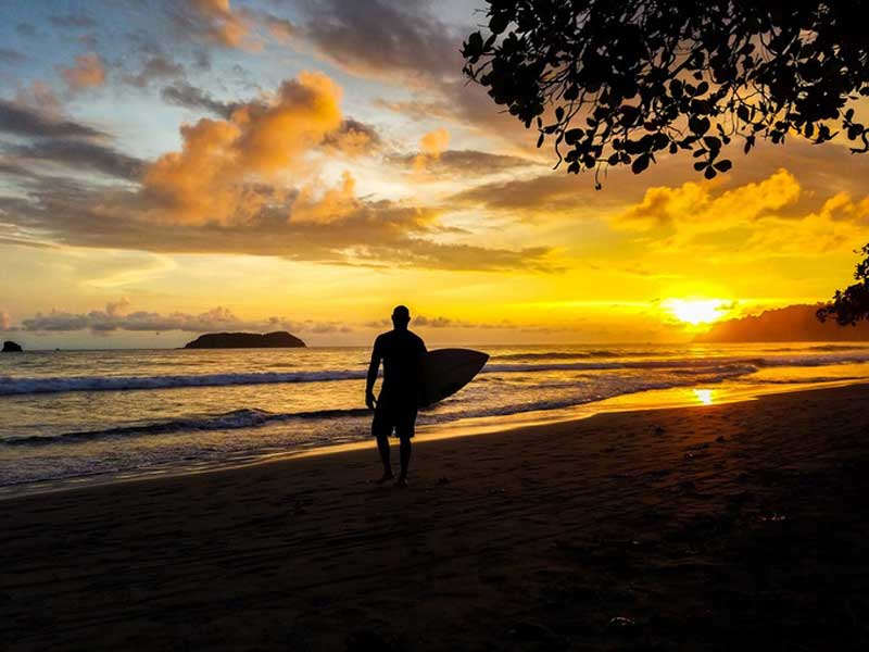 A man holding a surfboard while standing on a beach.