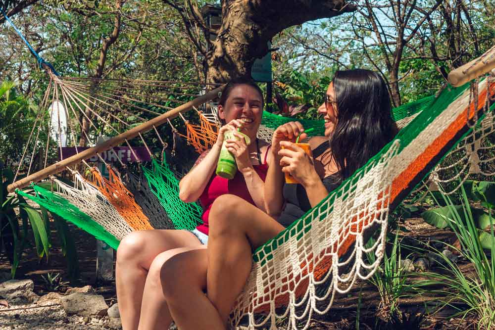 A couple of women sitting in a hammock.