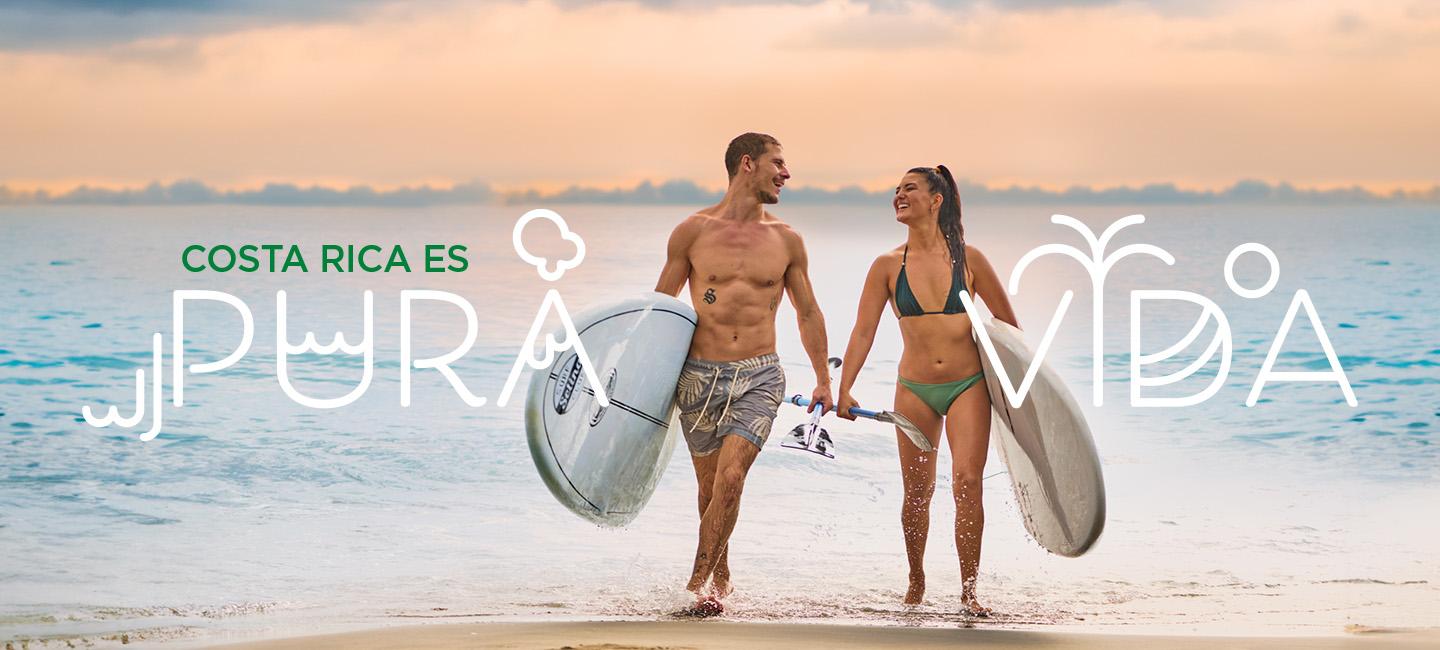couple walking on beach with surfboards and "pura vida" text around them