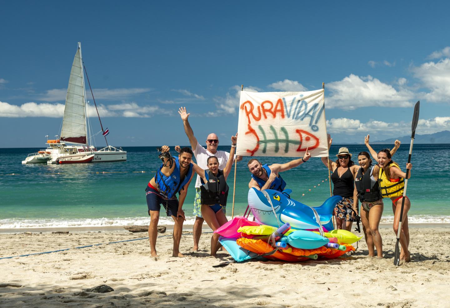 People on beach with a pura vida sign