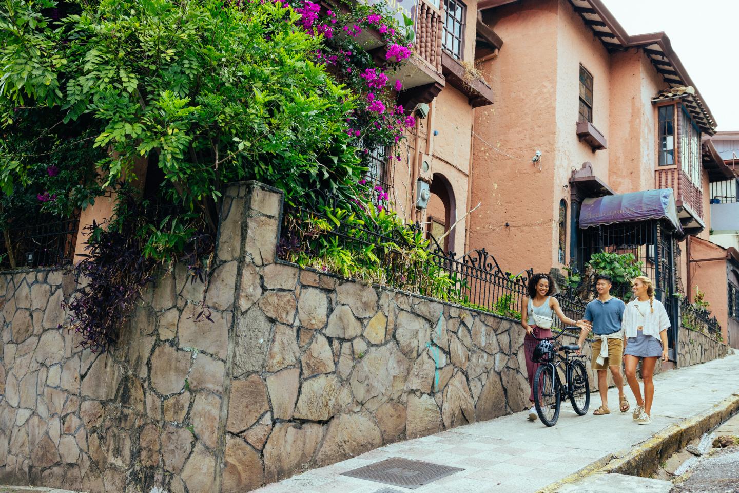 friends walking in a neighborhood with a bike