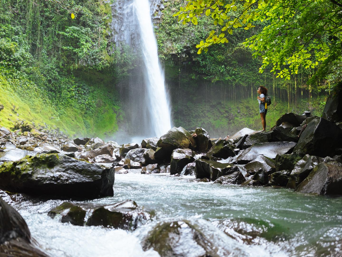 Woman standing next to waterfall in jungle