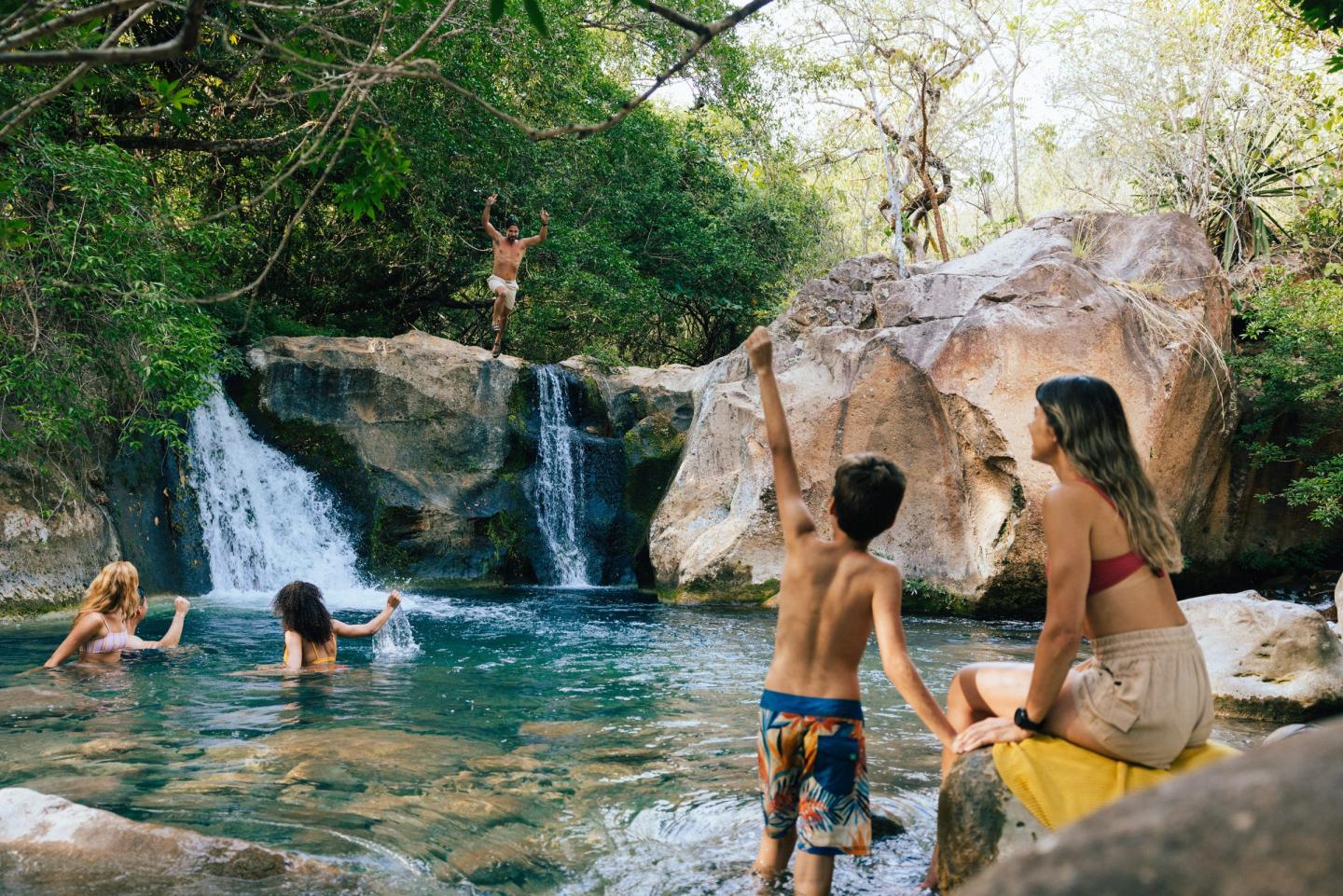 Father jumping and cheering at a waterfall at Las Chorreras, Hacienda Guachipelin